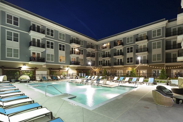 Resort-style pool at Amorance Apartments with lounge seating and sun umbrellas, offering a luxurious retreat for residents