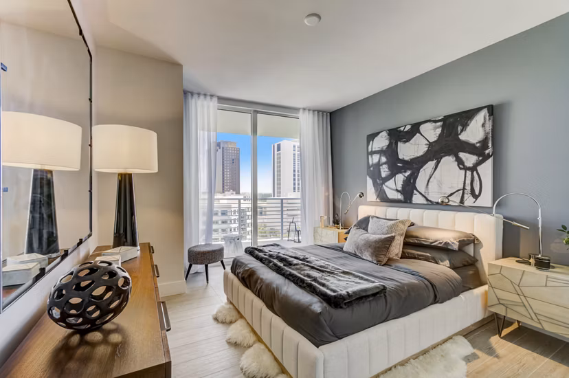 Cozy bedroom featuring modern decor and large windows at Alluvion Las Olas Apartments