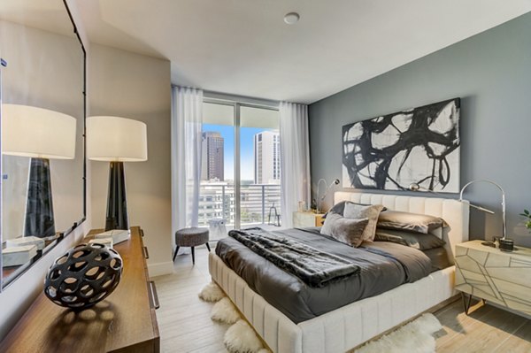 Cozy bedroom featuring modern decor and large windows at Alluvion Las Olas Apartments