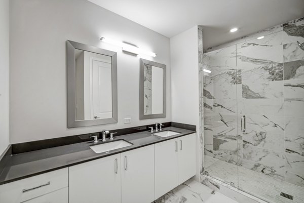 Modern bathroom with dual sinks and glass shower in Alluvion Las Olas Apartments