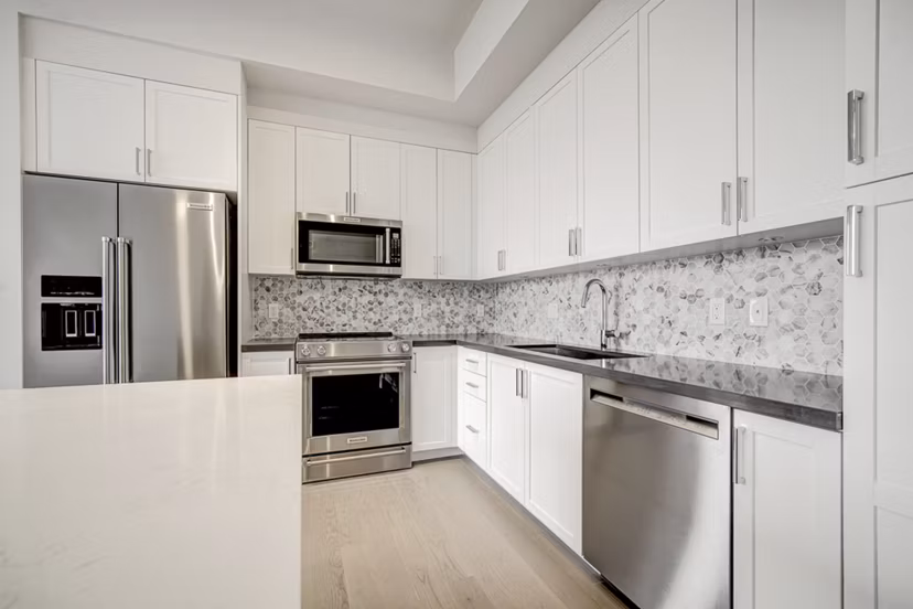 Modern kitchen with stainless steel appliances and quartz countertops in Alluvion Las Olas Apartments