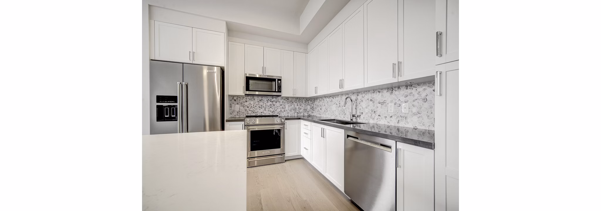 Modern kitchen with stainless steel appliances and quartz countertops in Alluvion Las Olas Apartments
