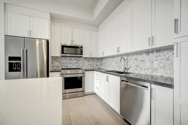 Modern kitchen with stainless steel appliances and quartz countertops in Alluvion Las Olas Apartments