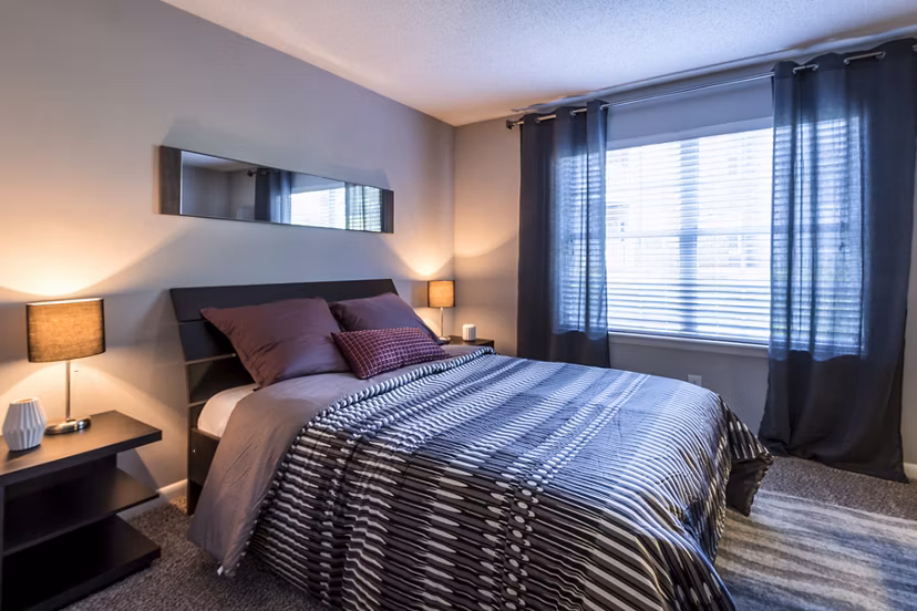 Comfortable bedroom with modern decor and large windows at Bridgeport Apartments