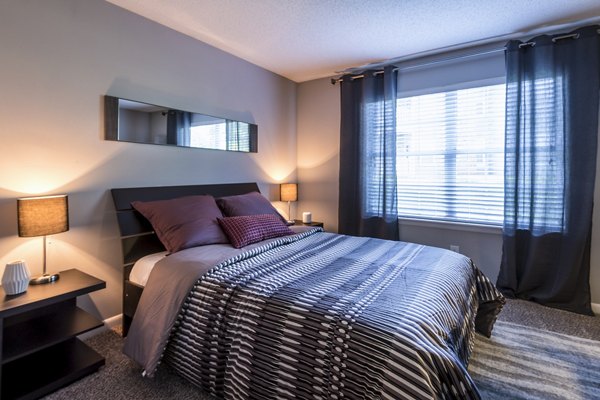 Comfortable bedroom with modern decor and large windows at Bridgeport Apartments