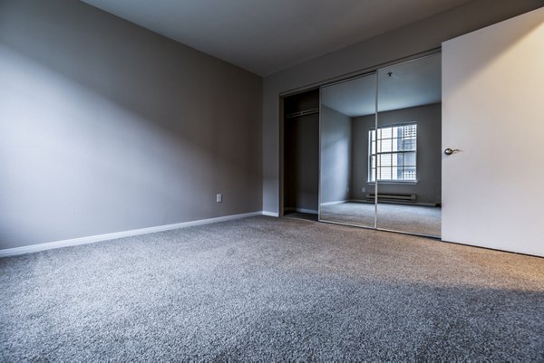 Modern bedroom featuring elegant decor and large windows at Huntington Park Apartments