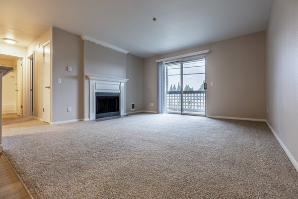 Spacious living room with modern furnishings at Huntington Park Apartments, featuring large windows and elegant design elements