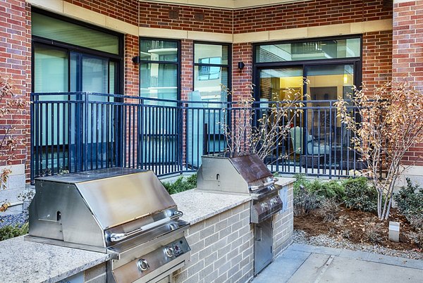 Grill area with modern seating and shaded tables at Raleigh at Sloans Lake Apartments