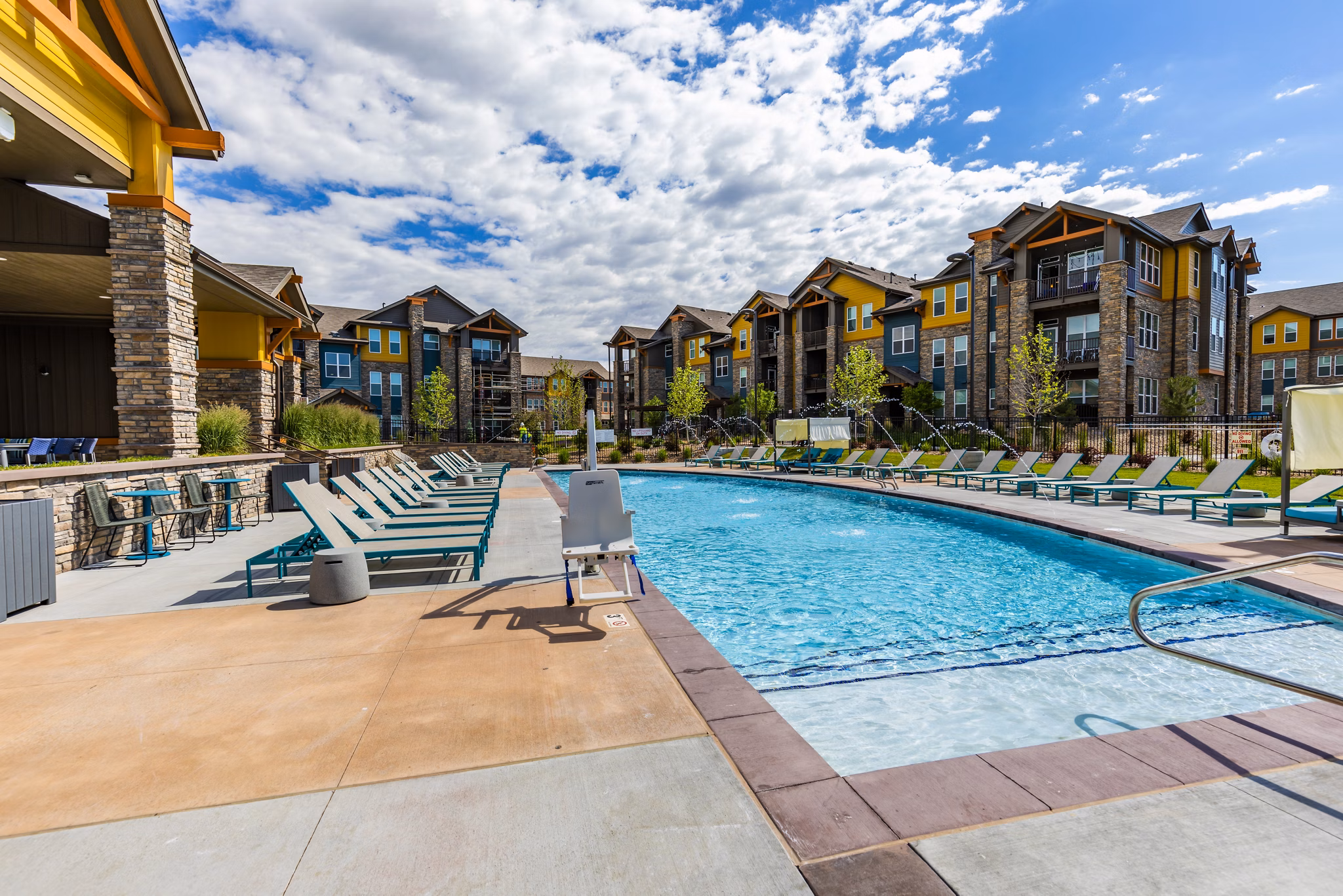 Modern outdoor pool area at The Tenzing Apartments with lounge seating and greenery