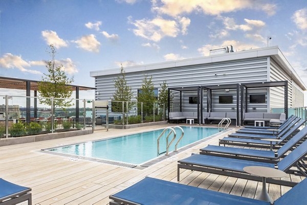 Modern outdoor pool at Bower Apartments with stylish lounge chairs and lush landscaping, offering a serene retreat for residents