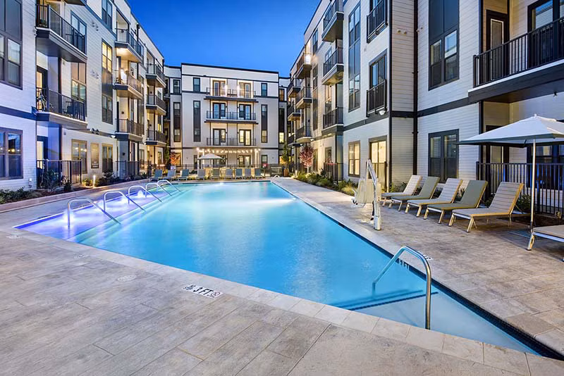 Community pool with lounge chairs at The Penrose Apartments offering relaxation and recreation for residents