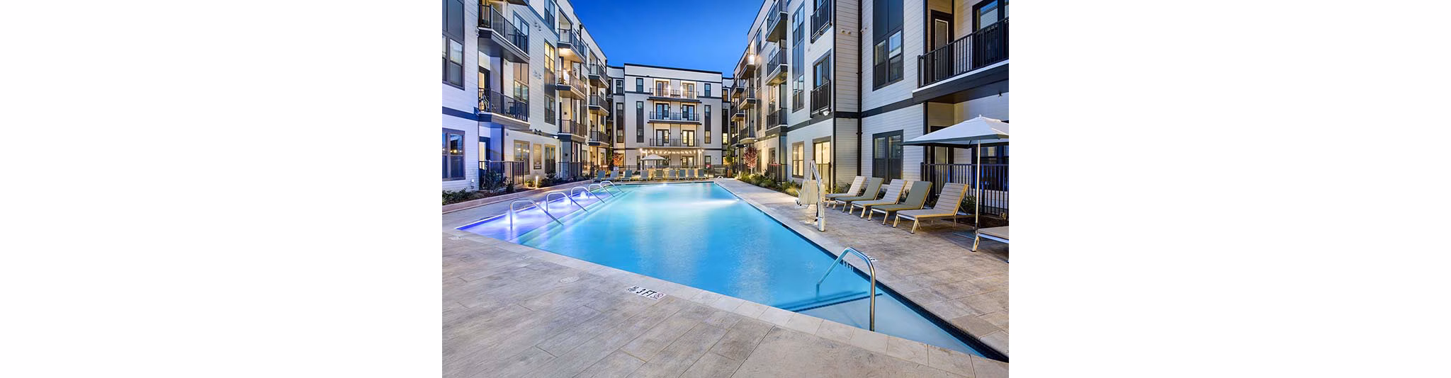 Community pool with lounge chairs at The Penrose Apartments offering relaxation and recreation for residents