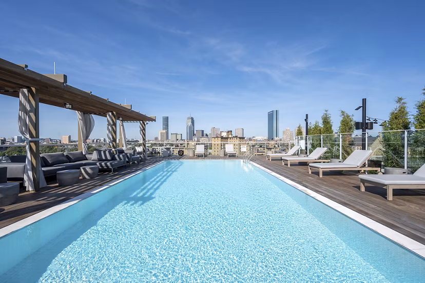 Resort-style pool with lounge chairs at The Smith Apartments, offering luxurious outdoor relaxation in a tranquil setting