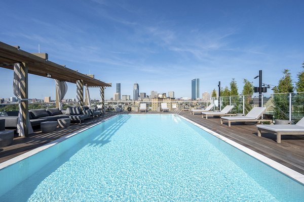 Resort-style pool with lounge chairs at The Smith Apartments, offering luxurious outdoor relaxation in a tranquil setting
