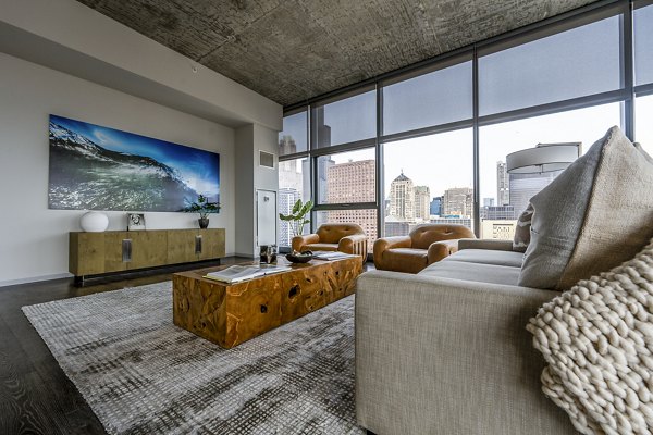 Spacious living room with modern decor in Imprint Apartments, featuring large windows and stylish furnishings for comfortable living