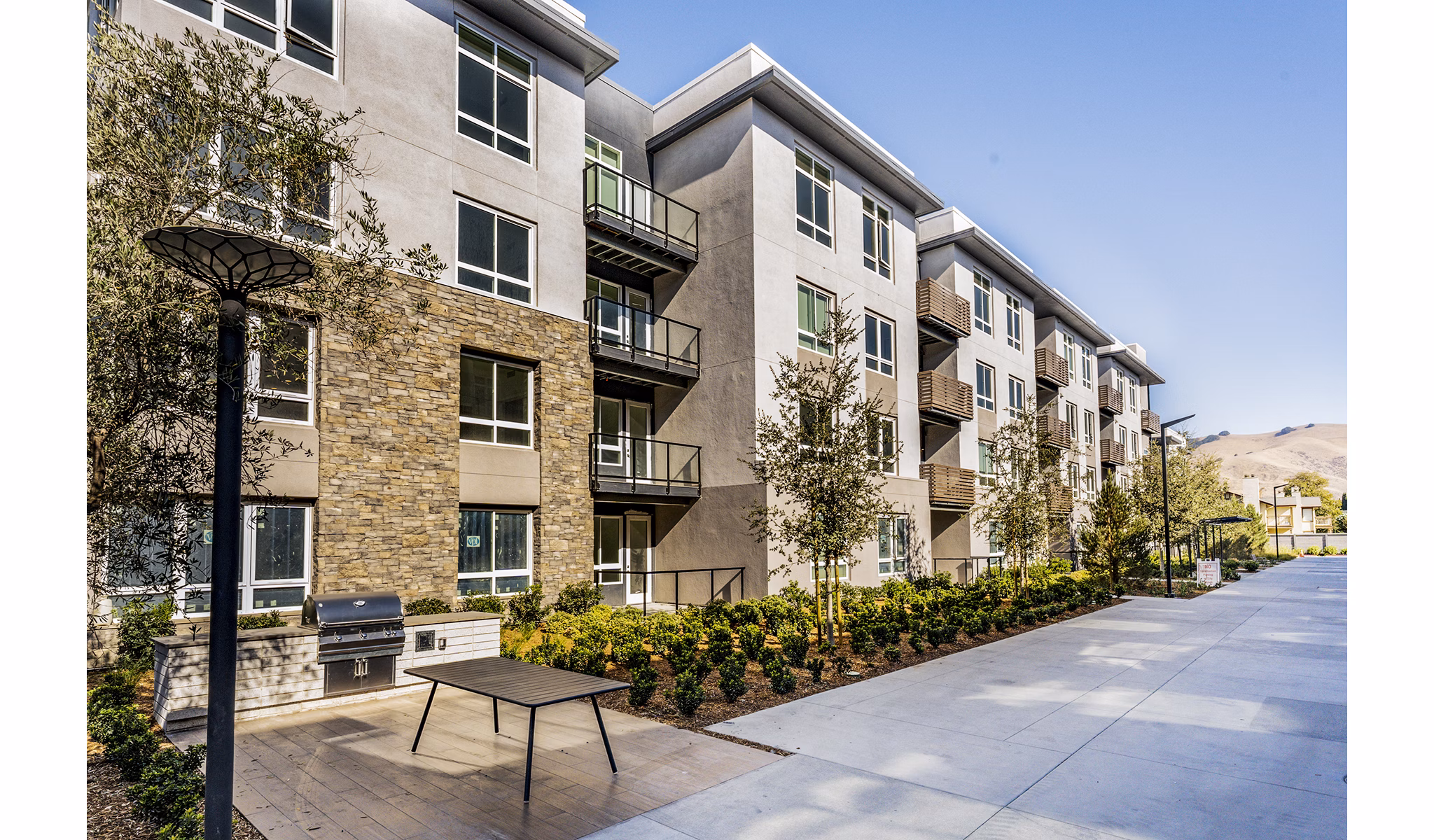 Outdoor grill area at The Asher Apartments featuring modern BBQ stations and ample seating for residents to enjoy in a communal setting