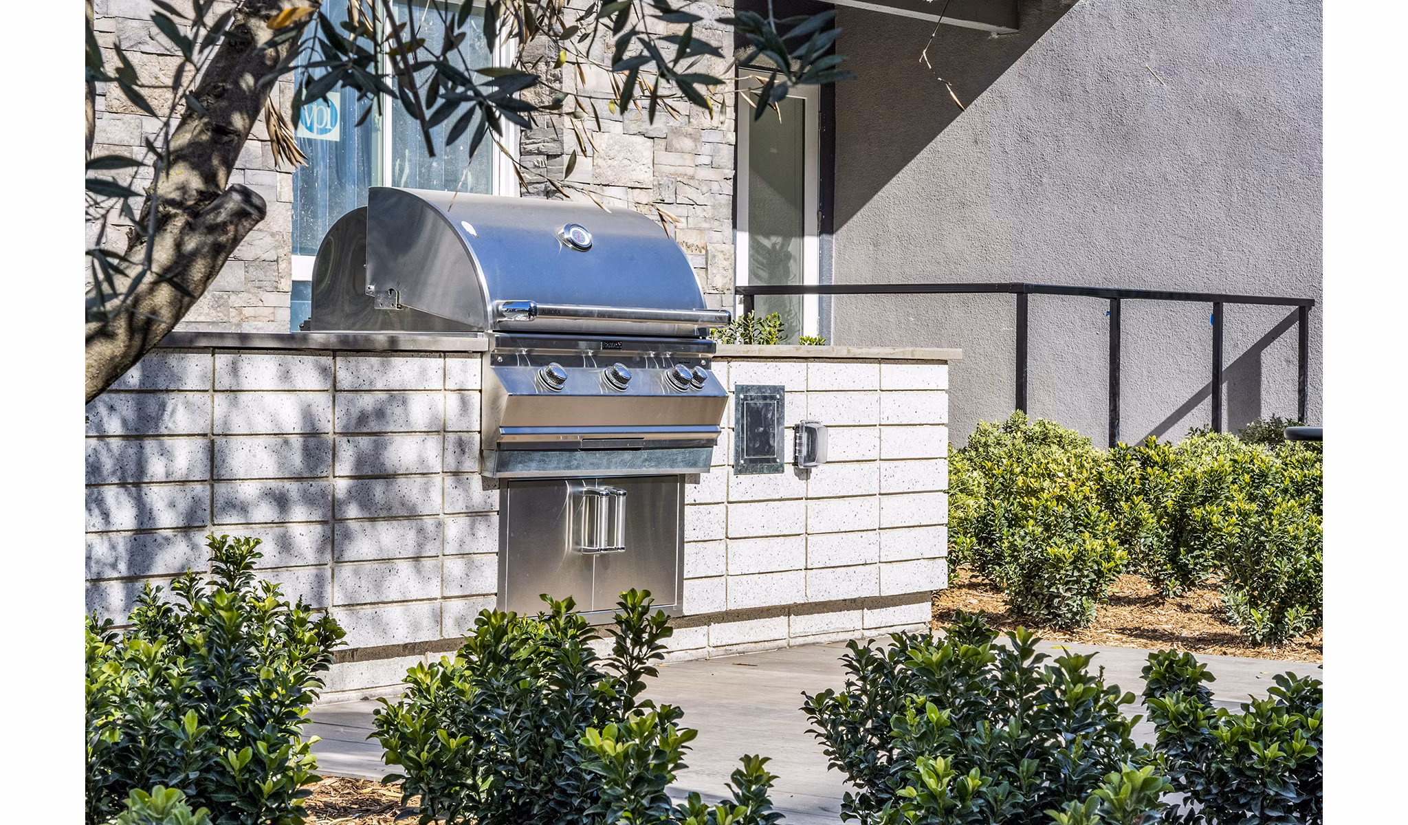 Outdoor grill area surrounded by lush greenery at The Asher Apartments