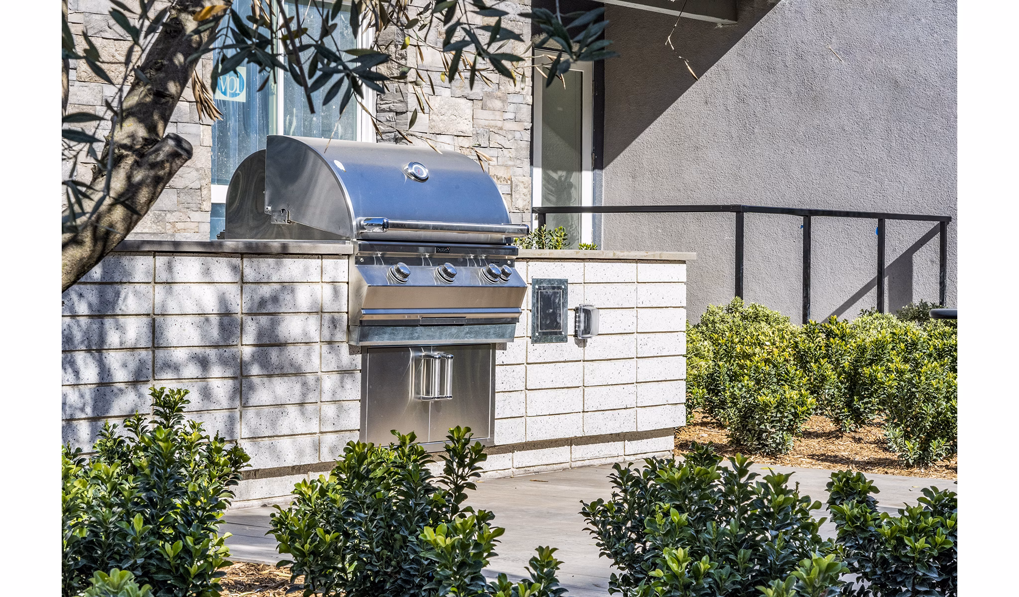 Outdoor grill area surrounded by lush greenery at The Asher Apartments