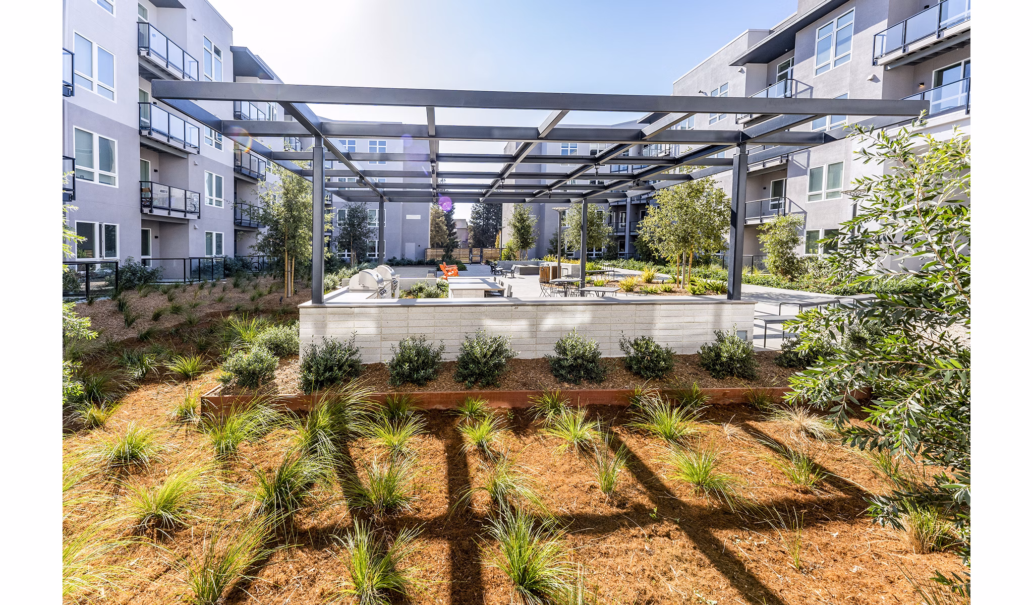 Grill area with modern barbecue stations at The Asher Apartments' luxury outdoor kitchen