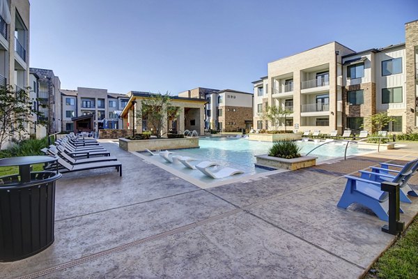 Poolside relaxation area at Lenox Reserve Apartments featuring luxury lounge chairs and lush landscaping