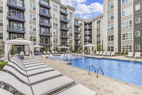 Sunlit outdoor pool surrounded by lush landscaping at Bainbridge South End Apartments