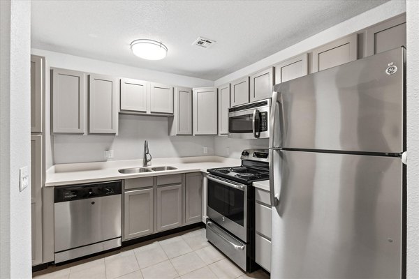 Modern kitchen with stainless steel appliances and granite countertops at The Haven Apartments