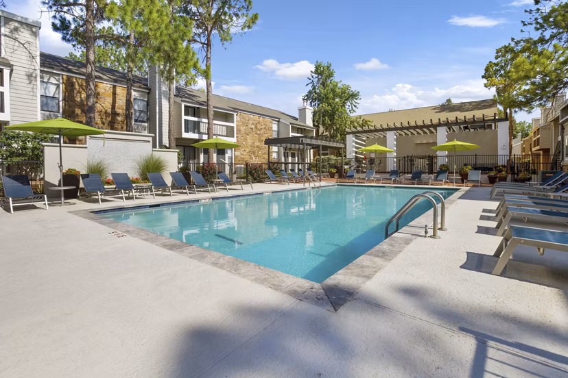 Sun-drenched poolside with loungers at Woodland Trails Apartments