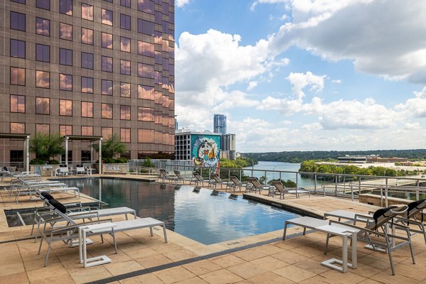 Luxurious outdoor pool at Ashton Austin Apartments with sun loungers and city view, offering premium relaxation in the heart of Austin