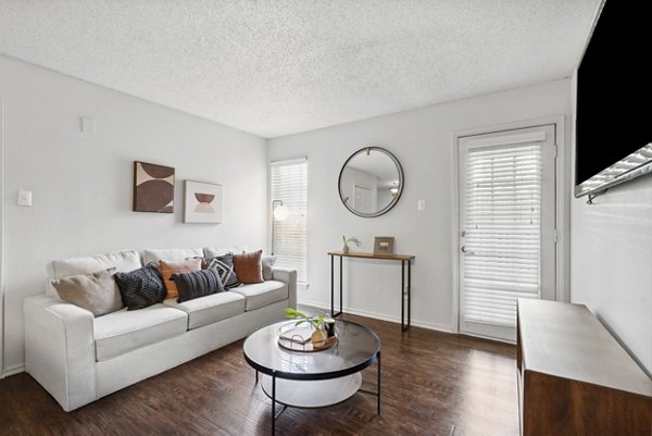 Spacious living room with modern decor featuring plush seating and a large window in Townlake of Coppell Apartments