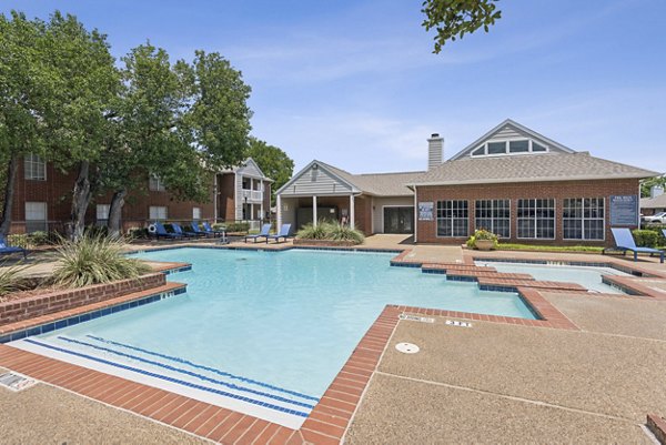 Serene outdoor pool area at Townlake of Coppell Apartments, featuring lush greenery and lounging chairs