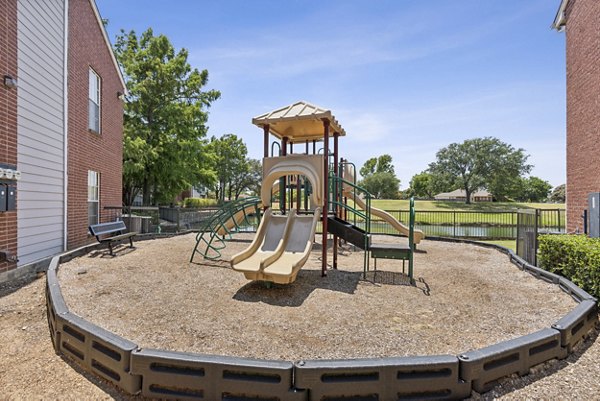 Playground with colorful structures at Townlake of Coppell Apartments, ideal for family fun and outdoor recreation