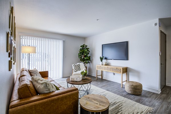 Open concept living room with modern furniture and large windows at Lumen Apartments