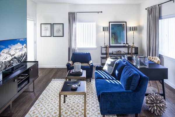 Spacious living room with modern decor in Riverwalk Apartments, offering luxury living with abundant natural light and stylish furnishings