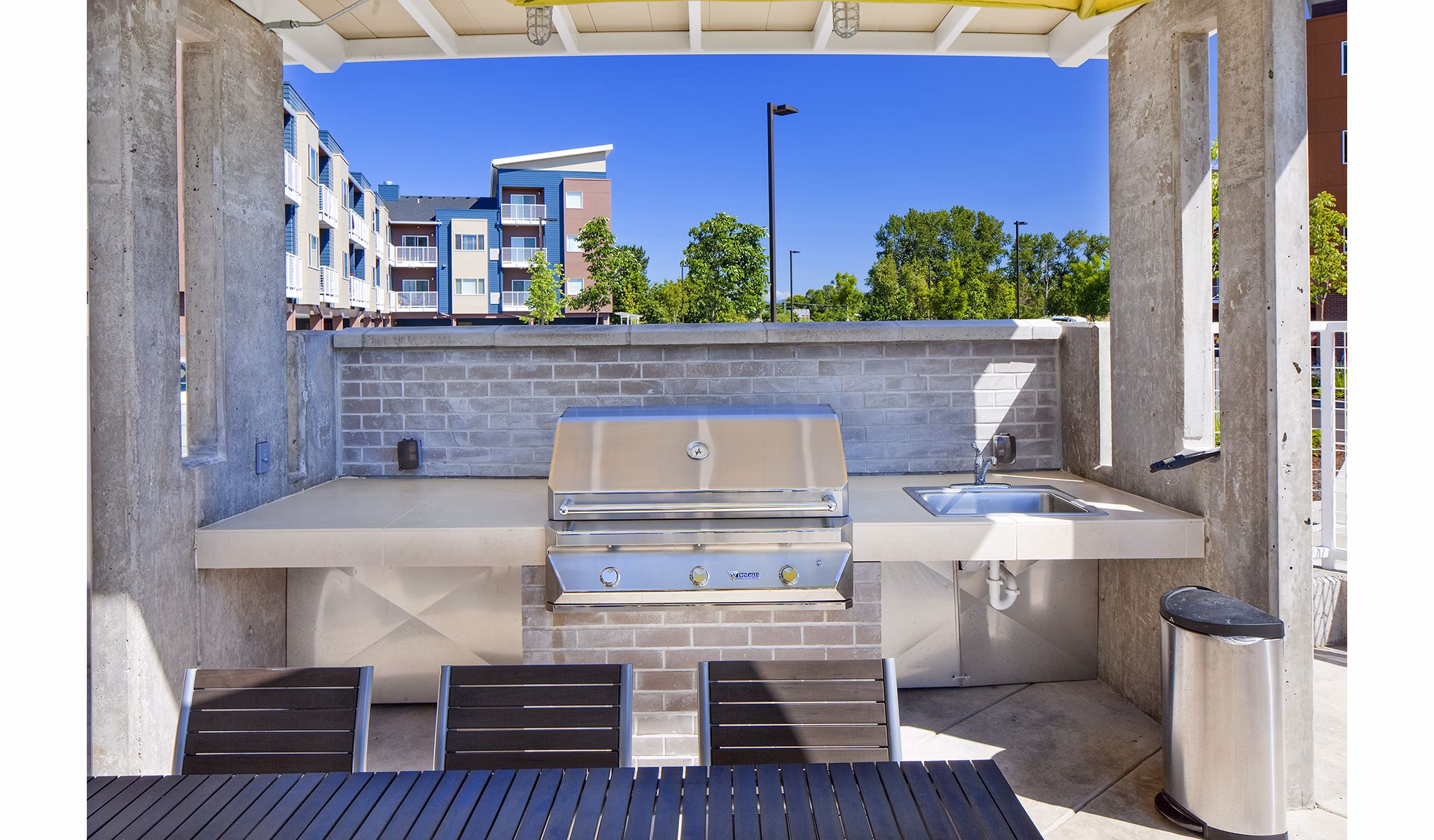 Outdoor grill area with modern seating at Riverwalk Apartments, offering a vibrant social space for residents