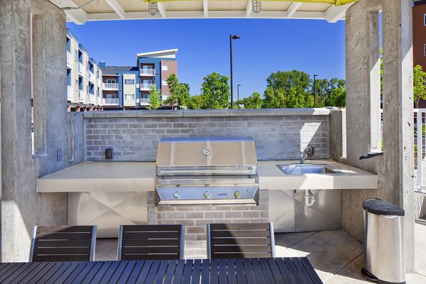 Outdoor grill area with modern seating at Riverwalk Apartments, offering a vibrant social space for residents