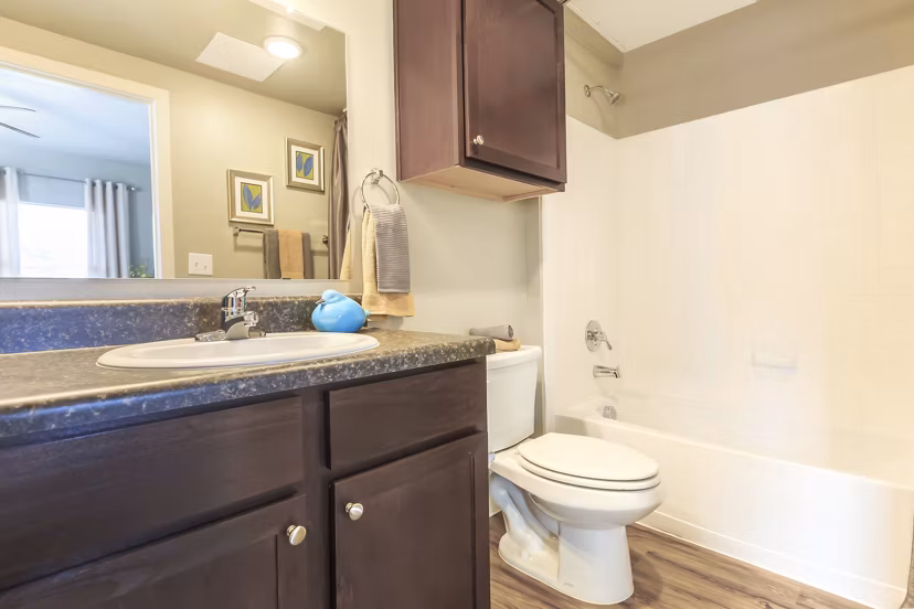 Modern bathroom with sleek fixtures and large mirror at Vantage at Boerne Apartments