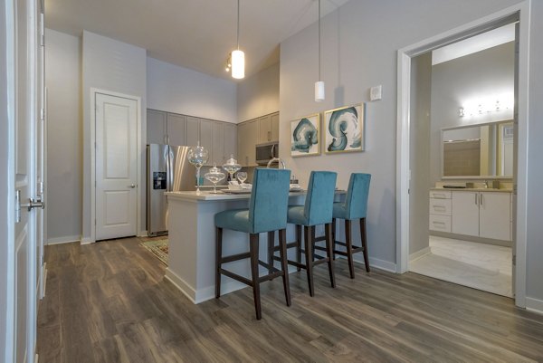 Dining area with modern furnishings at Aston City Springs Apartments, featuring elegant lighting and sleek design elements