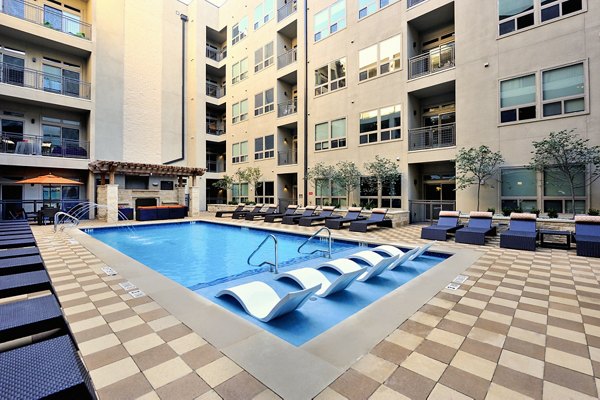 Poolside relaxation area at 422 at the Lake Apartments featuring sun loungers and greenery