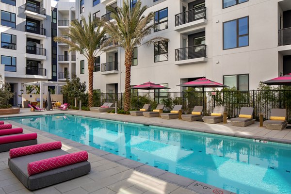 Sparkling outdoor pool at Savoy Apartments with surrounding lounge chairs in a luxurious setting