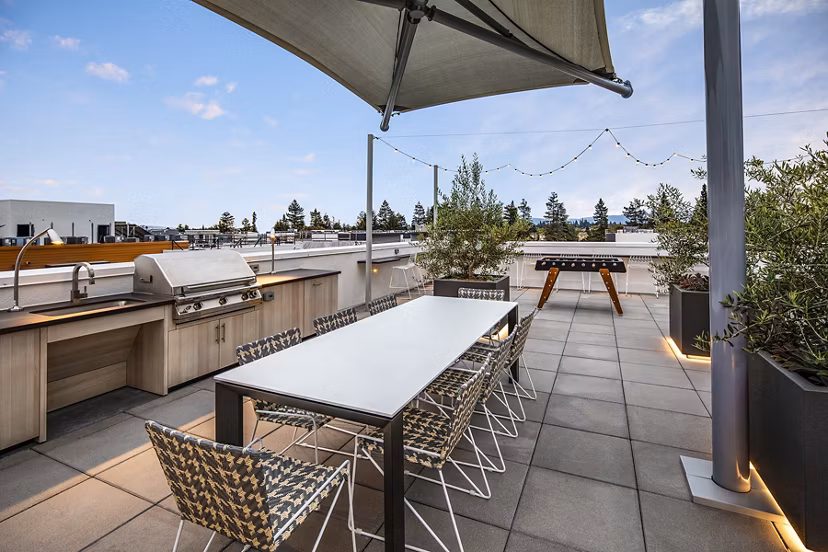 Outdoor grill area with modern seating at Savoy Apartments, offering a perfect space for social gatherings and dining under the sky