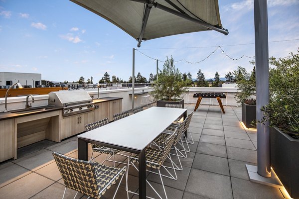 Outdoor grill area with modern seating at Savoy Apartments, offering a perfect space for social gatherings and dining under the sky
