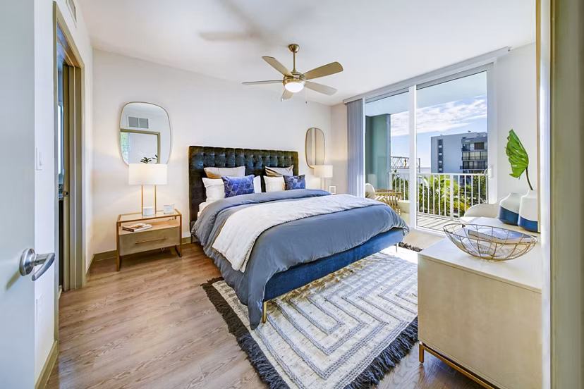 Bedroom with modern decor and large windows in Navette on the Bay Apartments, offering luxury living with scenic views