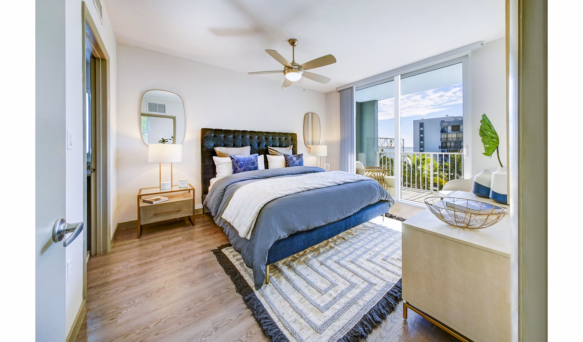 Bedroom with modern decor and large windows in Navette on the Bay Apartments, offering luxury living with scenic views