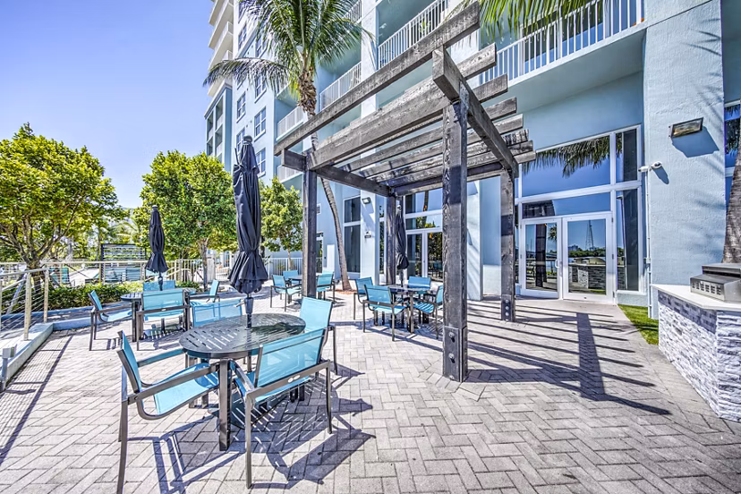 Outdoor grilling area with elegant patio setting at Navette on the Bay Apartments, ideal for social gatherings and enjoying waterside views