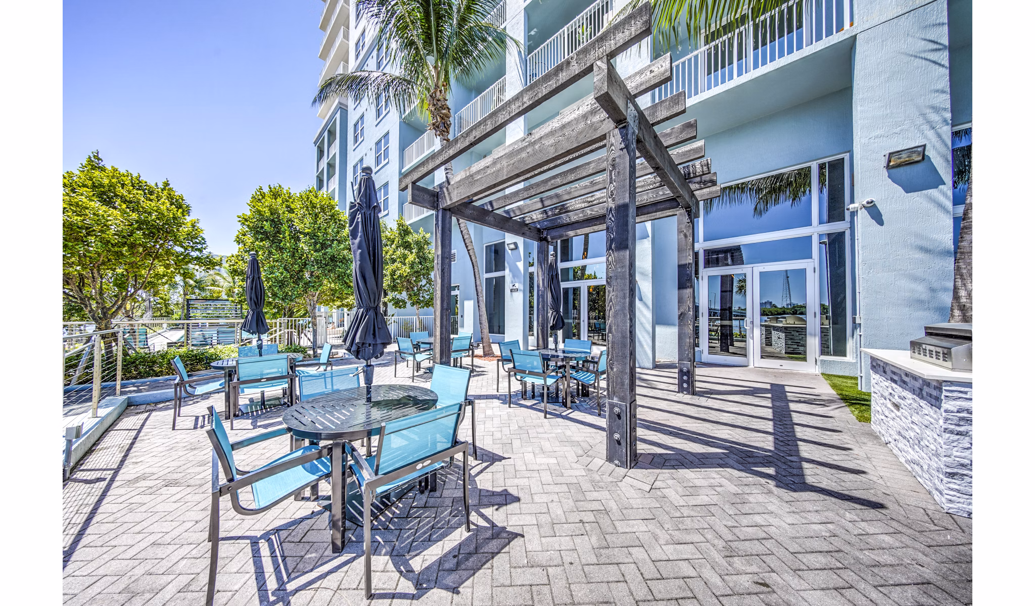 Outdoor grilling area with elegant patio setting at Navette on the Bay Apartments, ideal for social gatherings and enjoying waterside views