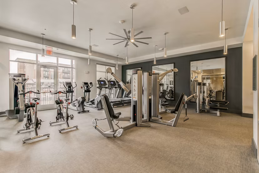 Modern fitness center equipped with cardio machines and free weights at Eastbank Riverwalk Apartments
