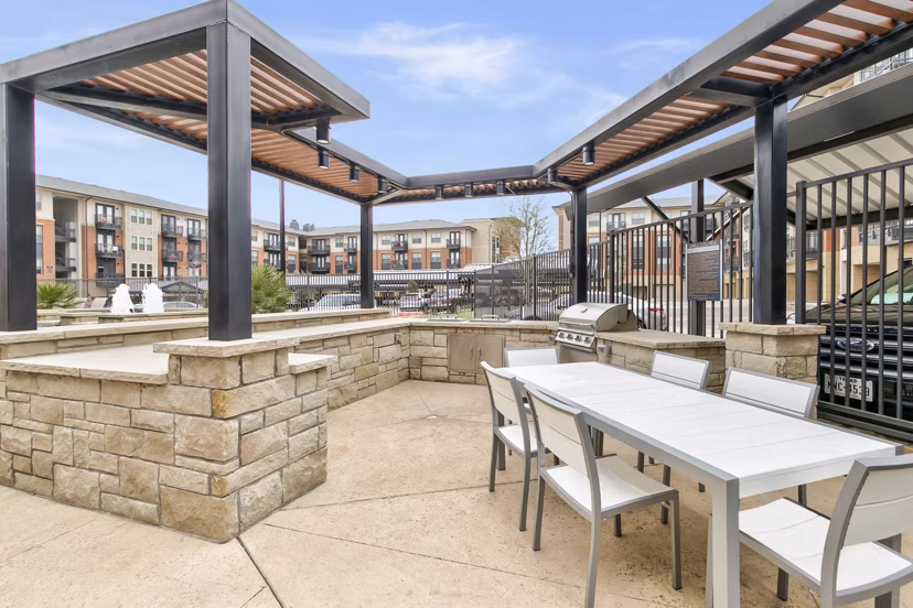 Outdoor grill area with stylish seating at Eastbank Riverwalk Apartments, offering a relaxing place for residents to gather and enjoy meals