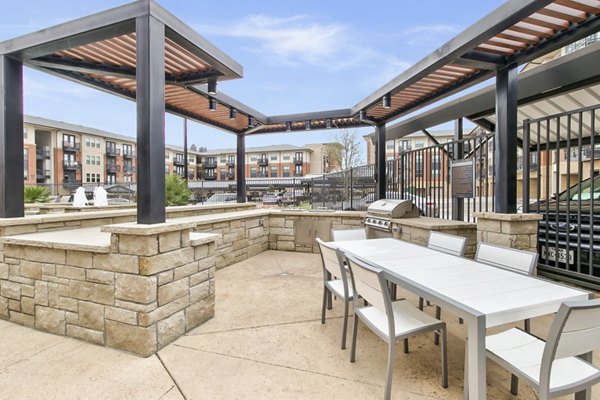Outdoor grill area with stylish seating at Eastbank Riverwalk Apartments, offering a relaxing place for residents to gather and enjoy meals