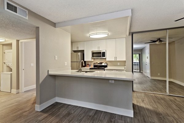 Modern kitchen with granite countertops and stainless appliances in Presidio at Rancho Del Oro Apartments