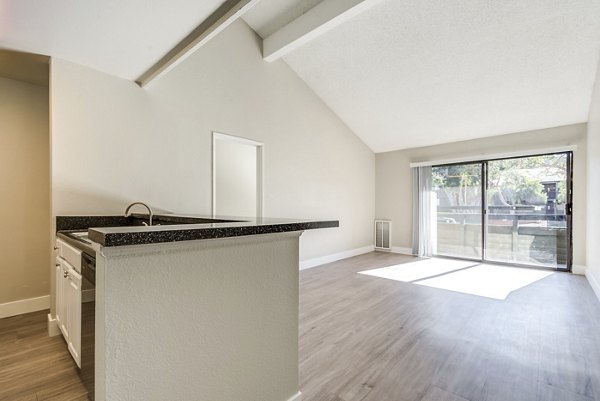 Spacious living room with modern furnishings and large windows at Presidio at Rancho Del Oro Apartments